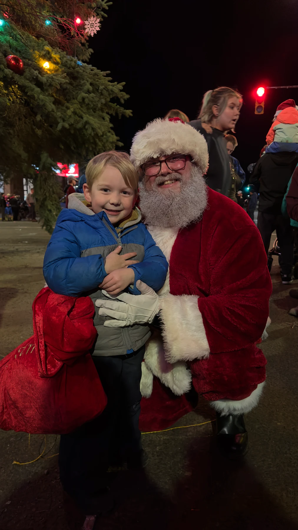 Santa Bryce holding his smiling young son at a Christmas celebration