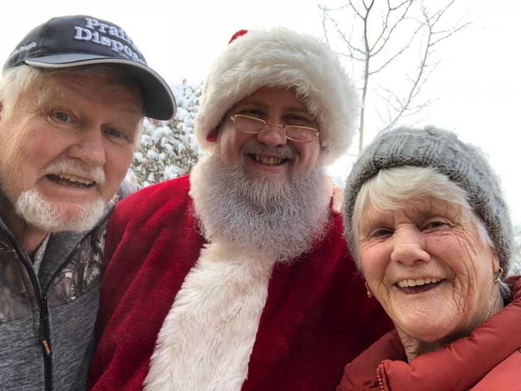 Santa Bryce smiling outdoors with two visitors