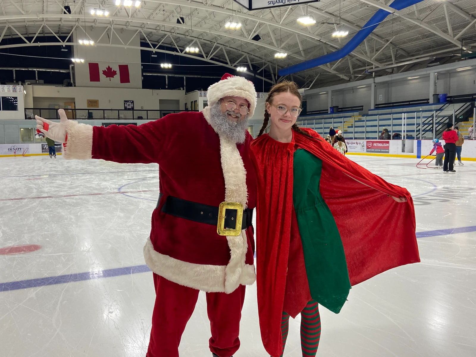 Santa Bryce and his helper spreading their arms on the ice rink